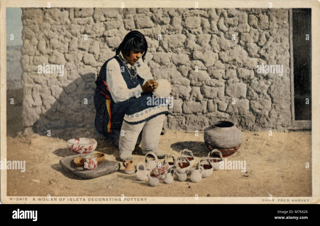A photograph depicting a woman from the Pueblo of Isleta decorating pottery, showcasing the craftsmanship and cultural heritage of Native American pottery. Stock Photo