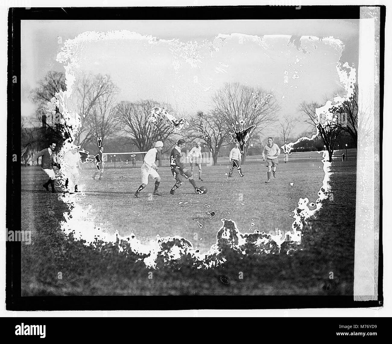 A photograph depicting a soccer game in action, showing players engaged in the sport during the early 20th century. The image captures the dynamics of the game. Stock Photo