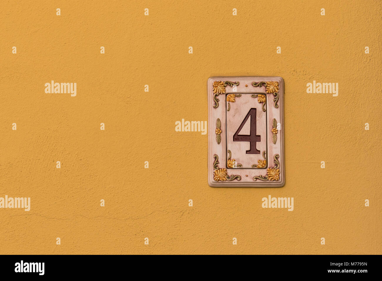 Ceramic house number 4 on yellow wall Stock Photo