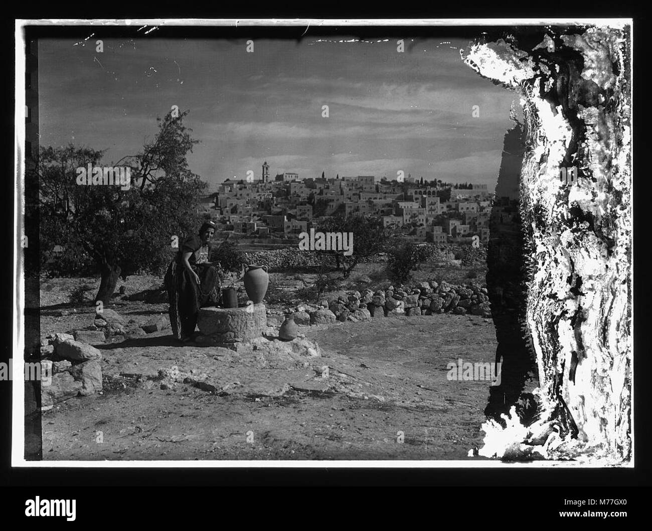 This image depicts Bethlehem from the south, with a woman named Sofie at the well, dressed in a richly embroidered costume. The scene captures a traditional moment in a biblical setting, highlighting cultural and religious practices. Stock Photo