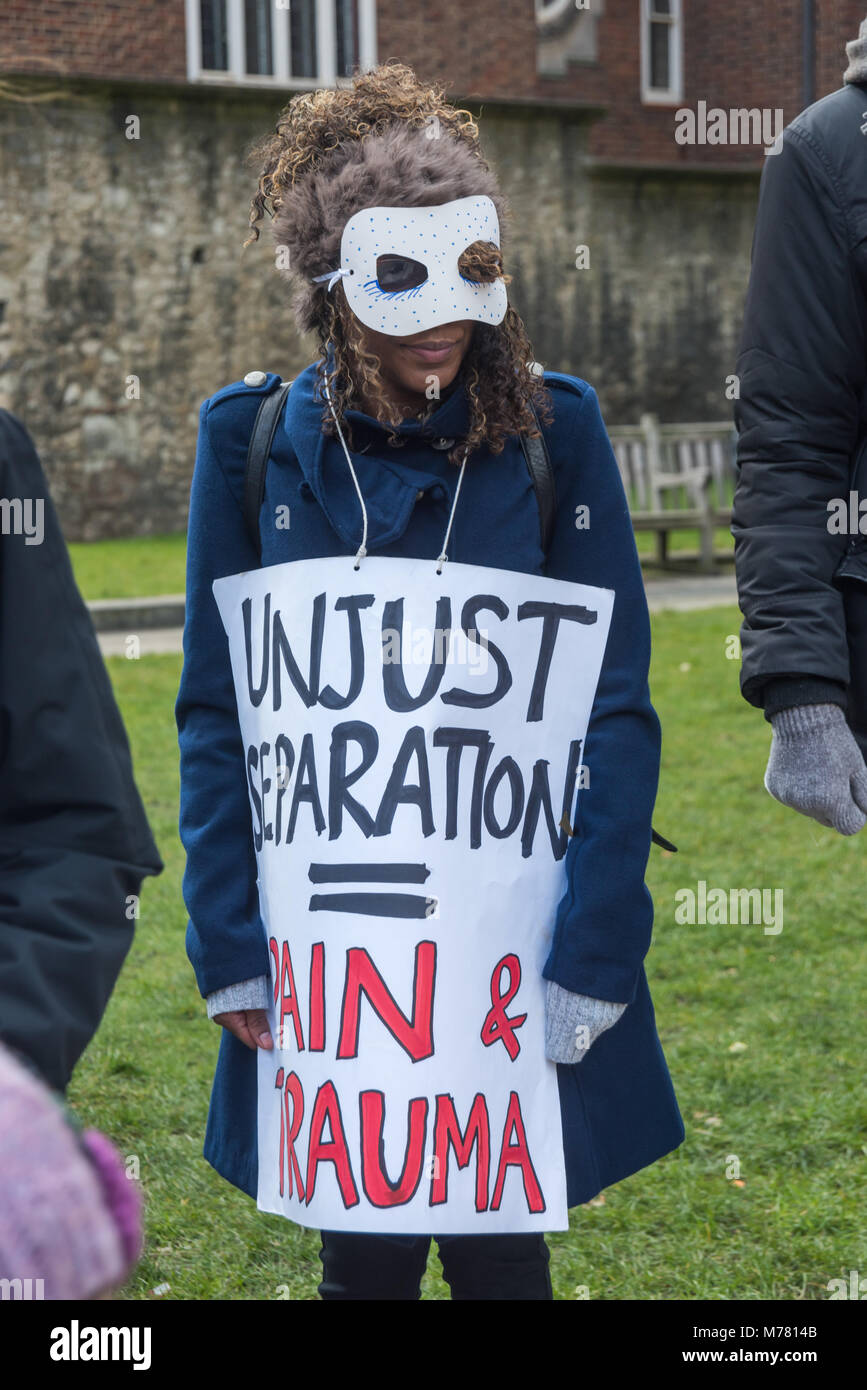 London, UK. 8th March 2018. A masked woman holds a poster 'Unjust Separation = Pain & trauma' at the Global Women's Strike mock trial of the Family Courts in an International Women’s Day protest in front of Parliament. Speakers included mothers who have had children unjustly removed and others who read out shocking comments made in court by judges. port Credit: Peter Marshall/Alamy Live News Stock Photo