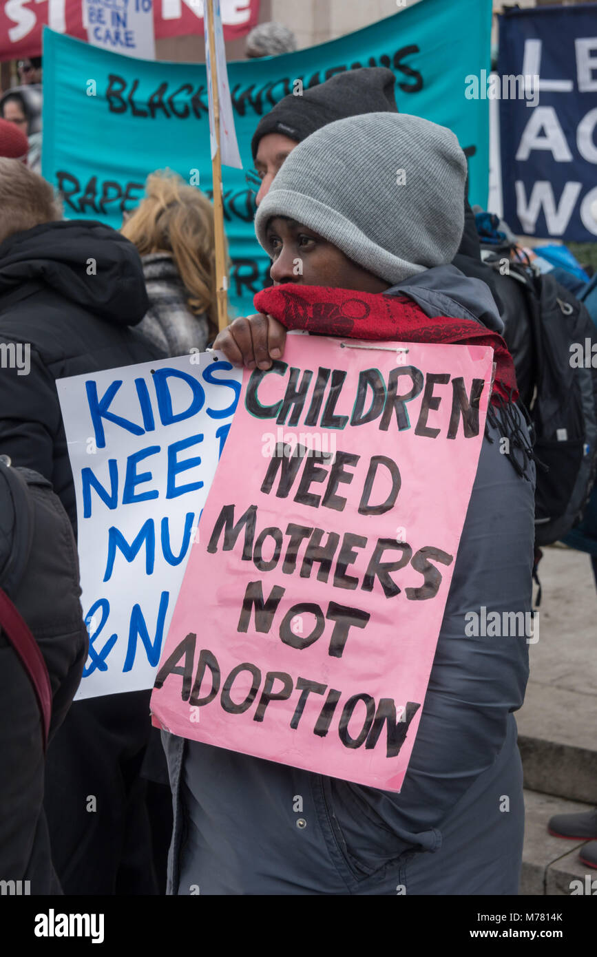 London, UK. 8th March 2018. A woman holds a poster 'Children Need Mothers Not Adoption' at the Global Women's Strike mock trial of the Family Courts in an International Women’s Day protest in front of Parliament. Speakers included mothers who have had children unjustly removed and others who read out shocking comments made in court by judges. portionate Credit: Peter Marshall/Alamy Live News Stock Photo