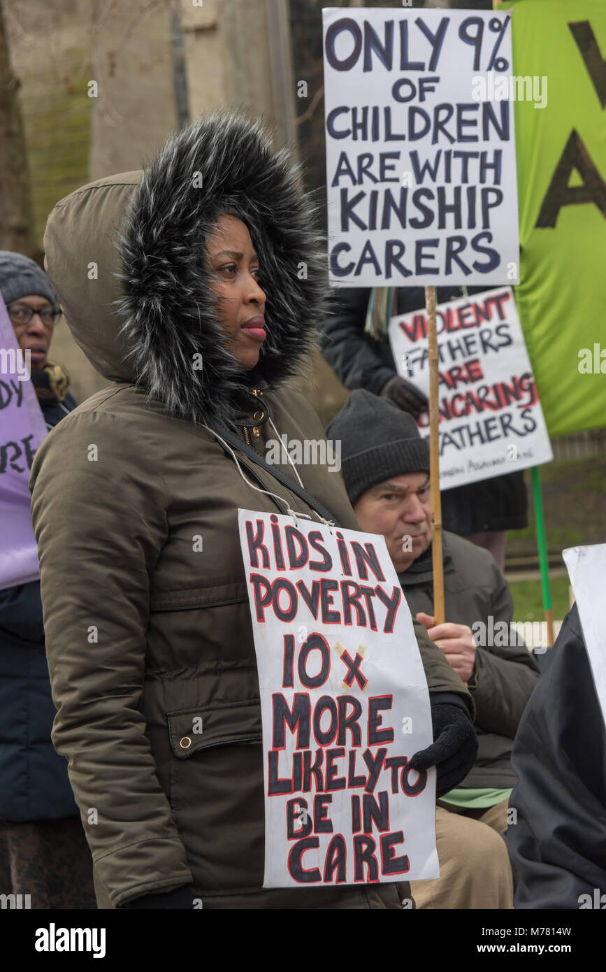 London, UK. 8th March 2018. A woman with a poster 'Kids in Poverty 10x more likely to be in care' at the Global Women's Strike mock trial of the Family Courts in an International Women’s Day protest in front of Parliament. Speakers included mothers who have had children unjustly removed and others who read out shocking comments made in court by judges. Credit: Peter Marshall/Alamy Live News Stock Photo