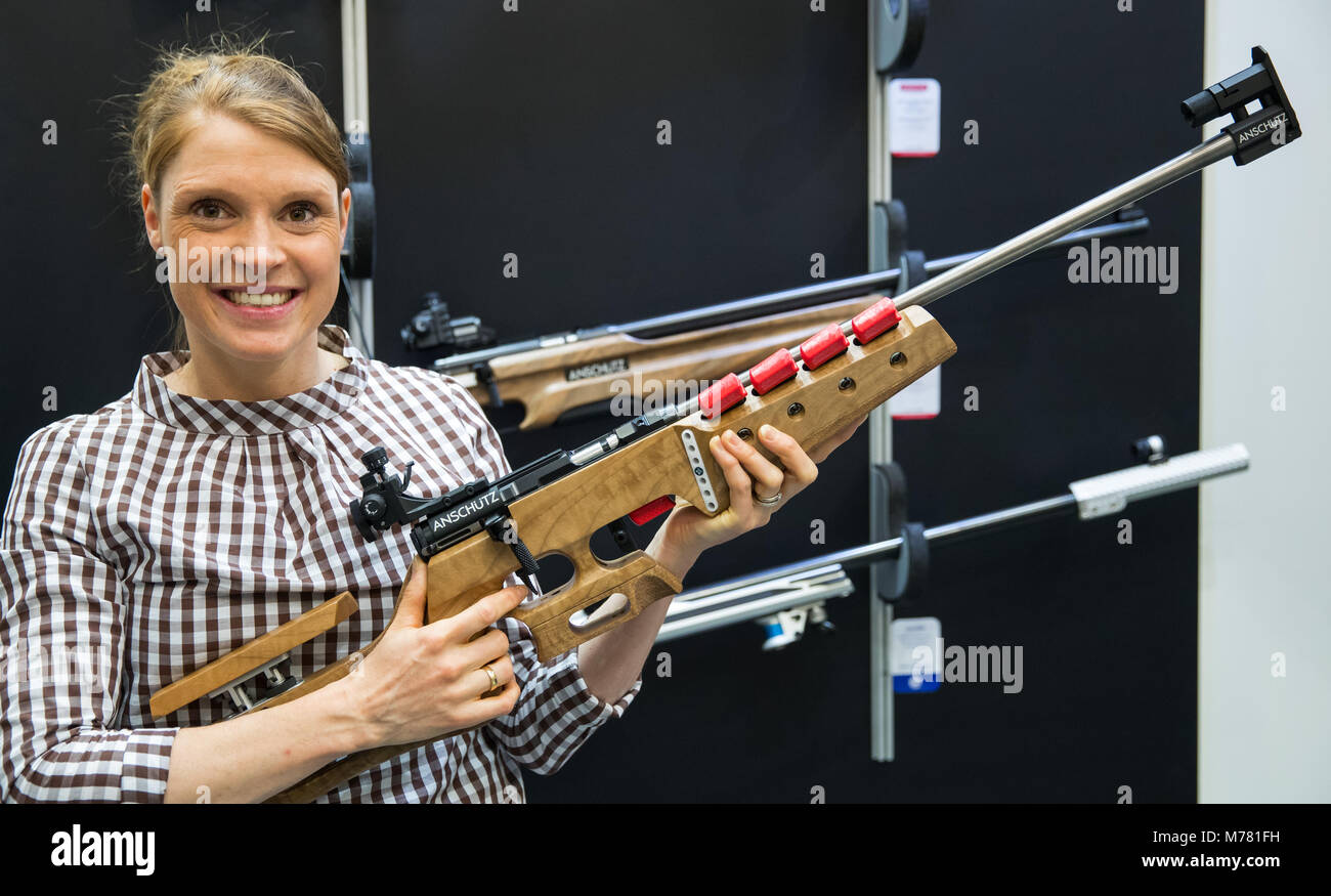 09 March 2018, Germany, Nuremberg: Evi Sachenbacher-Stehle, former German cross-country skier and biathlete, holds a rifle of the manufacturer Anschütz at the IWA OutdoorClassics gun fair, which is currently exhibiting guns and rifles for hunting and leisure. Photo: Daniel Karmann/dpa Stock Photo