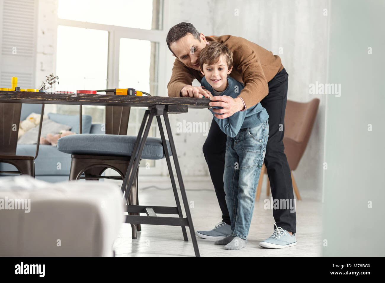 Happy father helping his son measure the table Stock Photo - Alamy