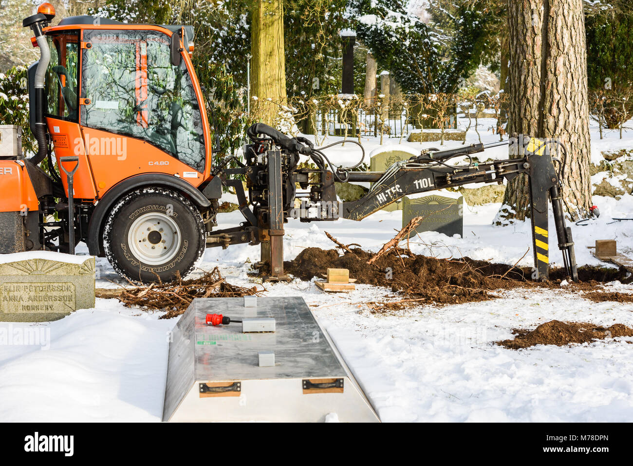 Ronneby, Sweden - March 1, 2018: Documentary of everyday life and environment. Holder C480 tractor used as a grave digger at a cemetery in winter. Roo Stock Photo