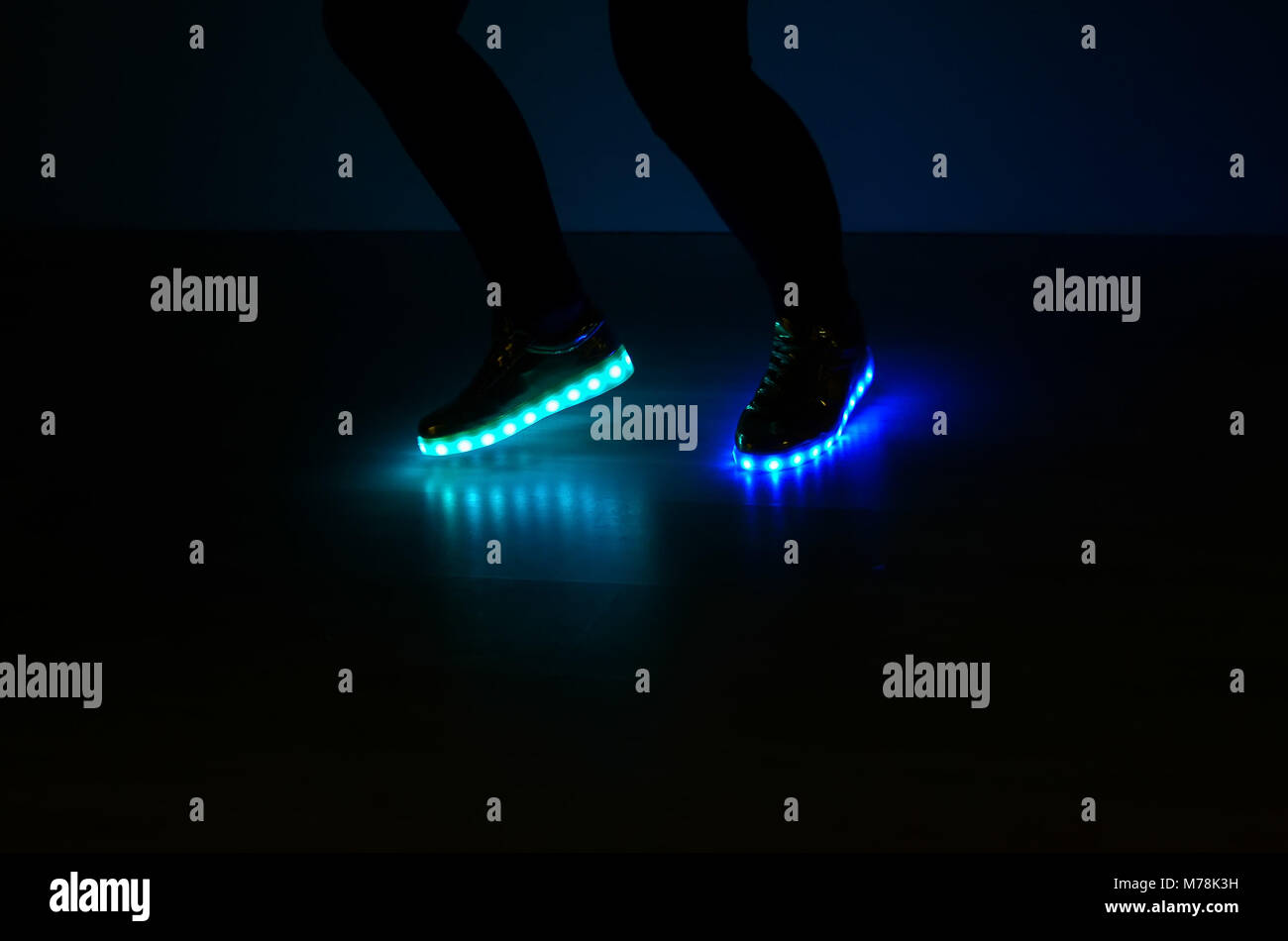 Fashionable sneakers with LED lighting on the legs of a girl with blue and azure colors Stock Photo