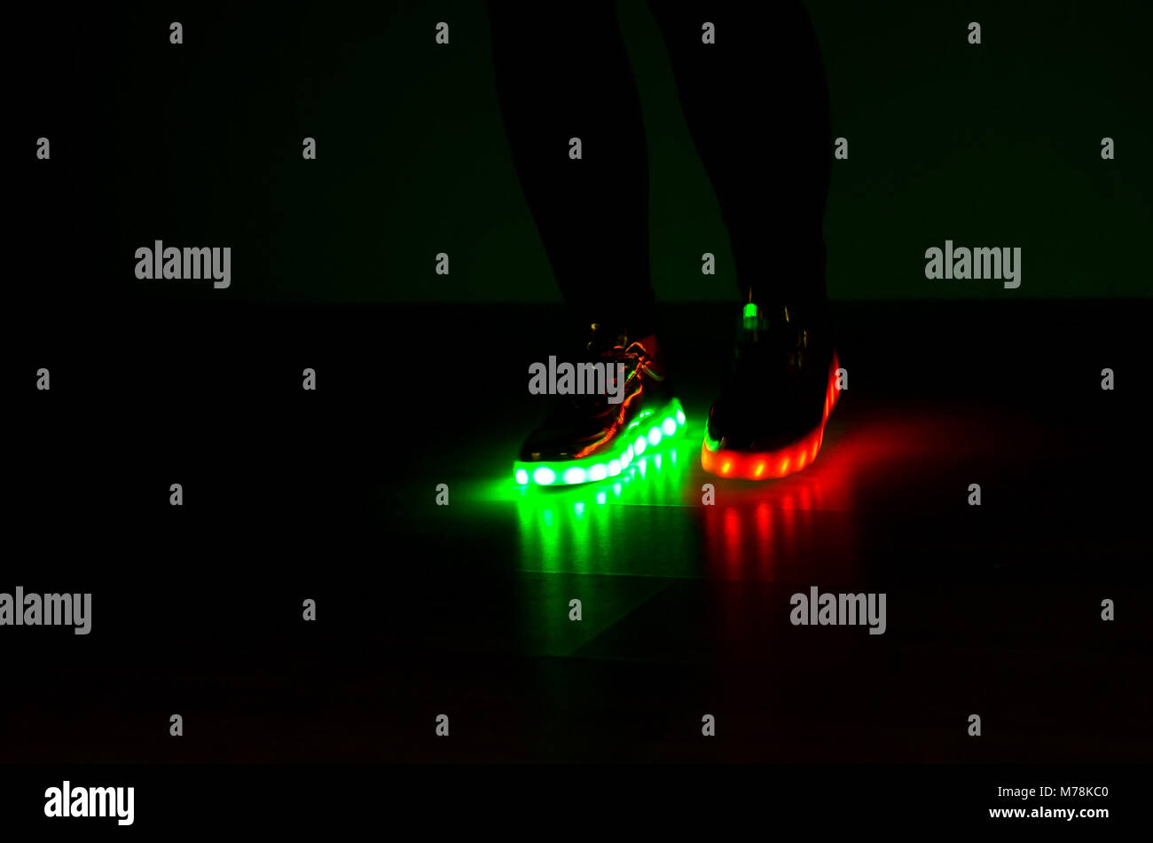 Fashionable sneakers with LED lighting on the legs of a girl with red and green colors Stock Photo