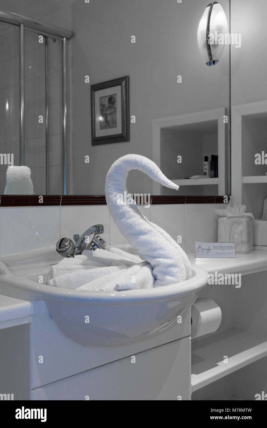 A folded towel swan in a hotel sink an example of towel animals, towel origami or the decorative art of towel folding Stock Photo