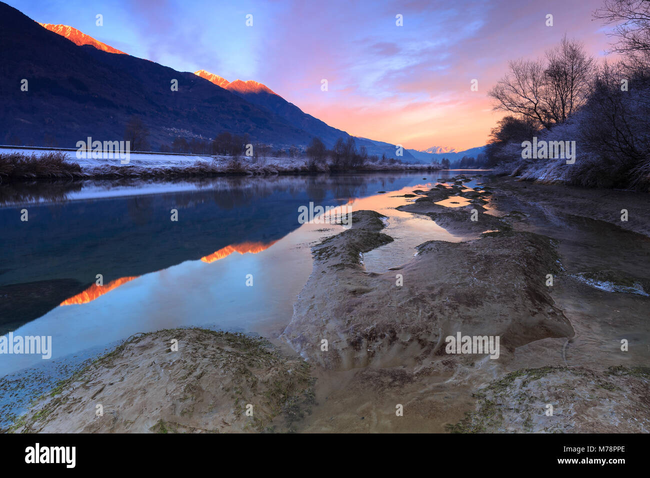 The colors of sunset are reflected in the Adda River, Valtellina ...