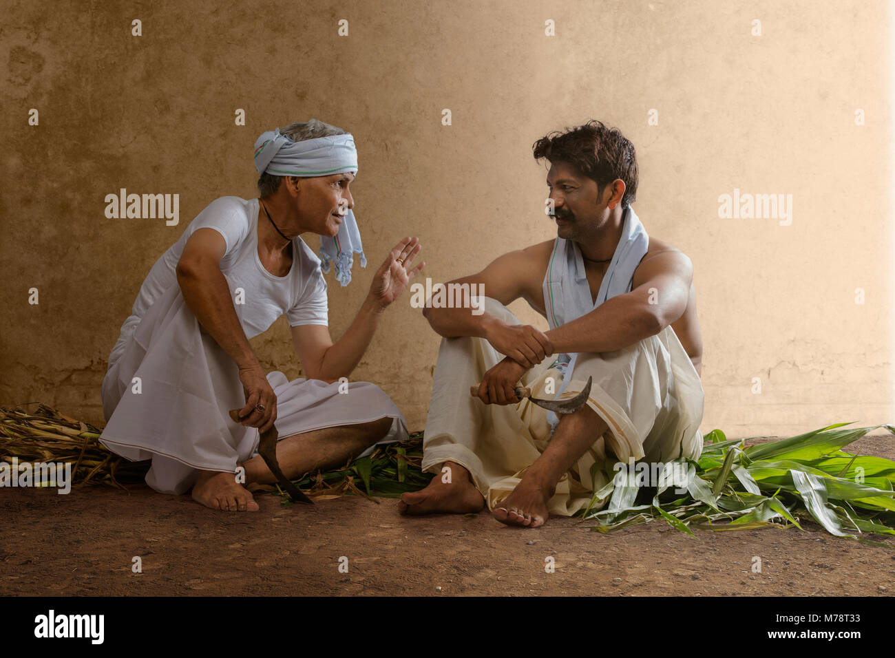 Two Indian farmer holding farming tools and talking Stock Photo