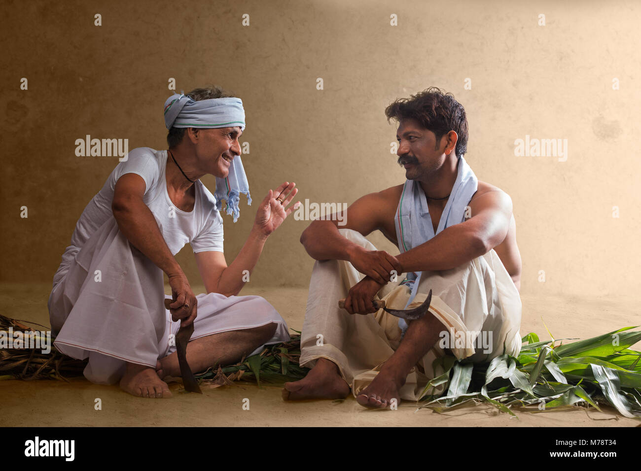Two Indian farmer holding farming tools and talking Stock Photo