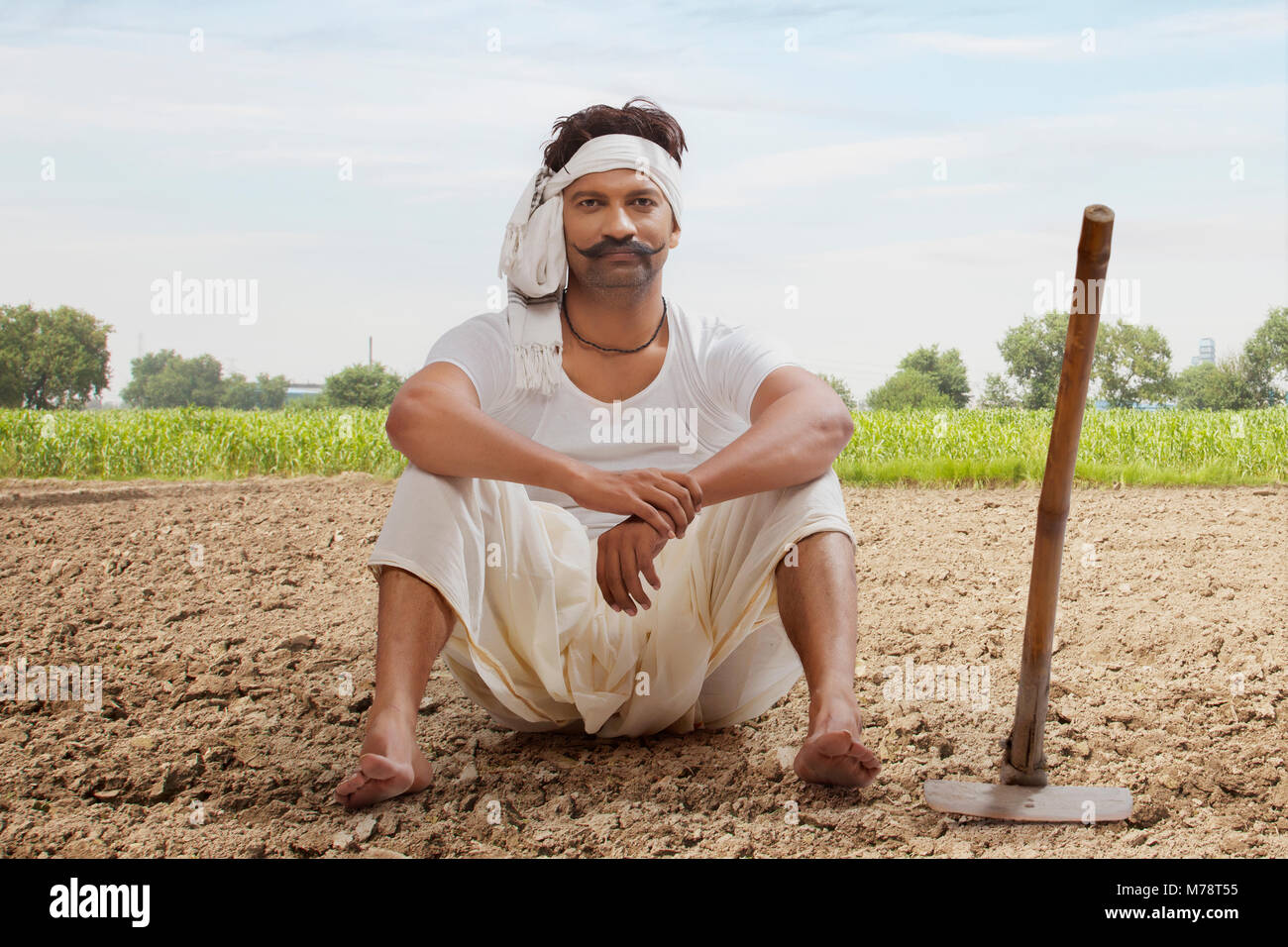 Farmer is sitting in field with hoe Stock Photo