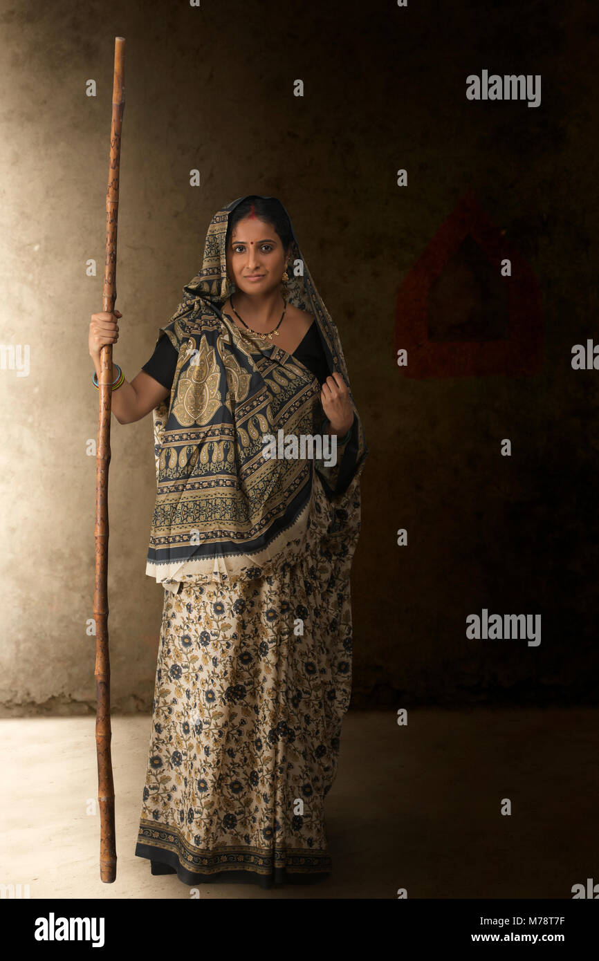 Portrait of woman in sari holding stick Stock Photo