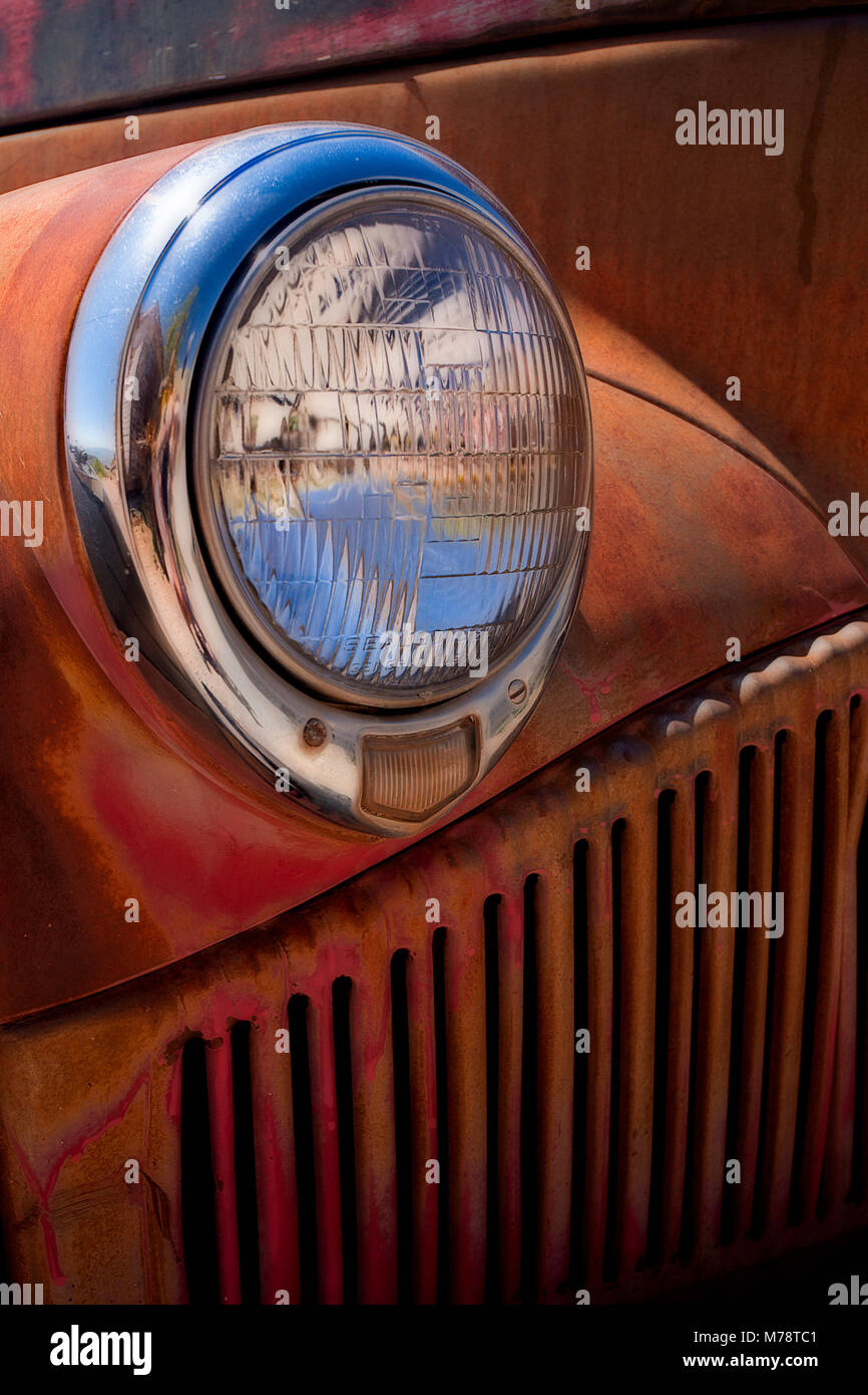 Chrome headlight on old rusty scrap automobile in the junkyard at Jerome, Arizona Stock Photo