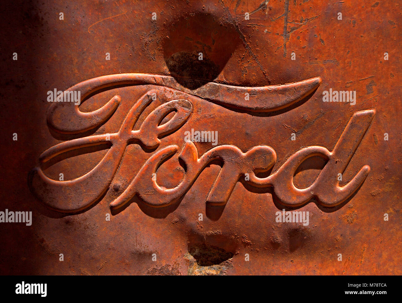 Dented old steel Ford logo on a scrap truck at Jerome junkyard, Arizona Stock Photo