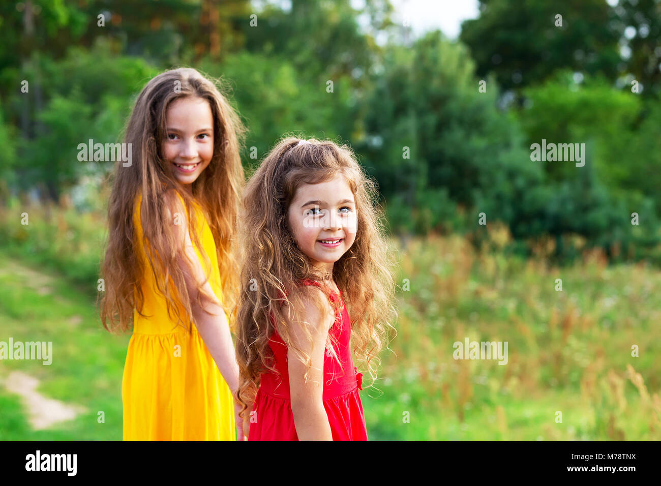 Two beautiful little girsl embracing and smiling at sunny summer day. Happy childhood concept Stock Photo