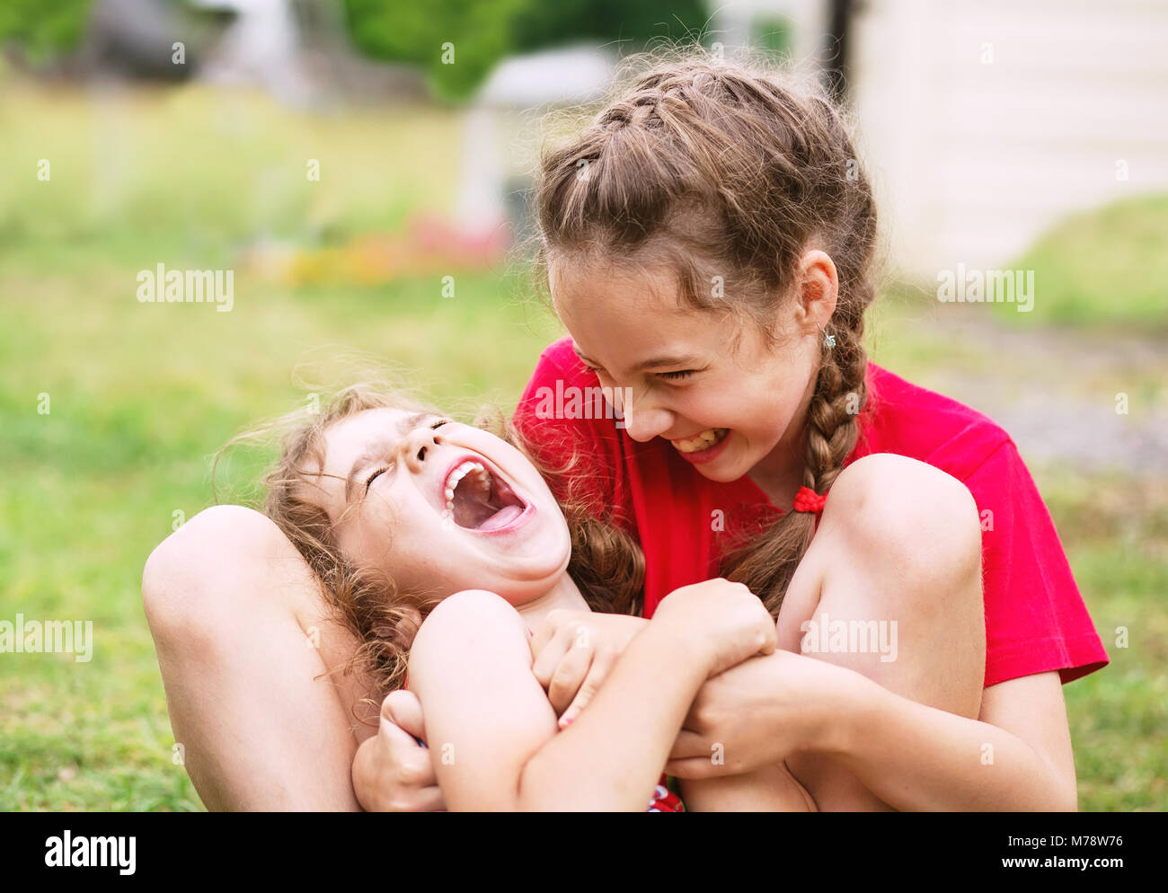 Two Happy little girls embracing and laughing at the park Stock Photo