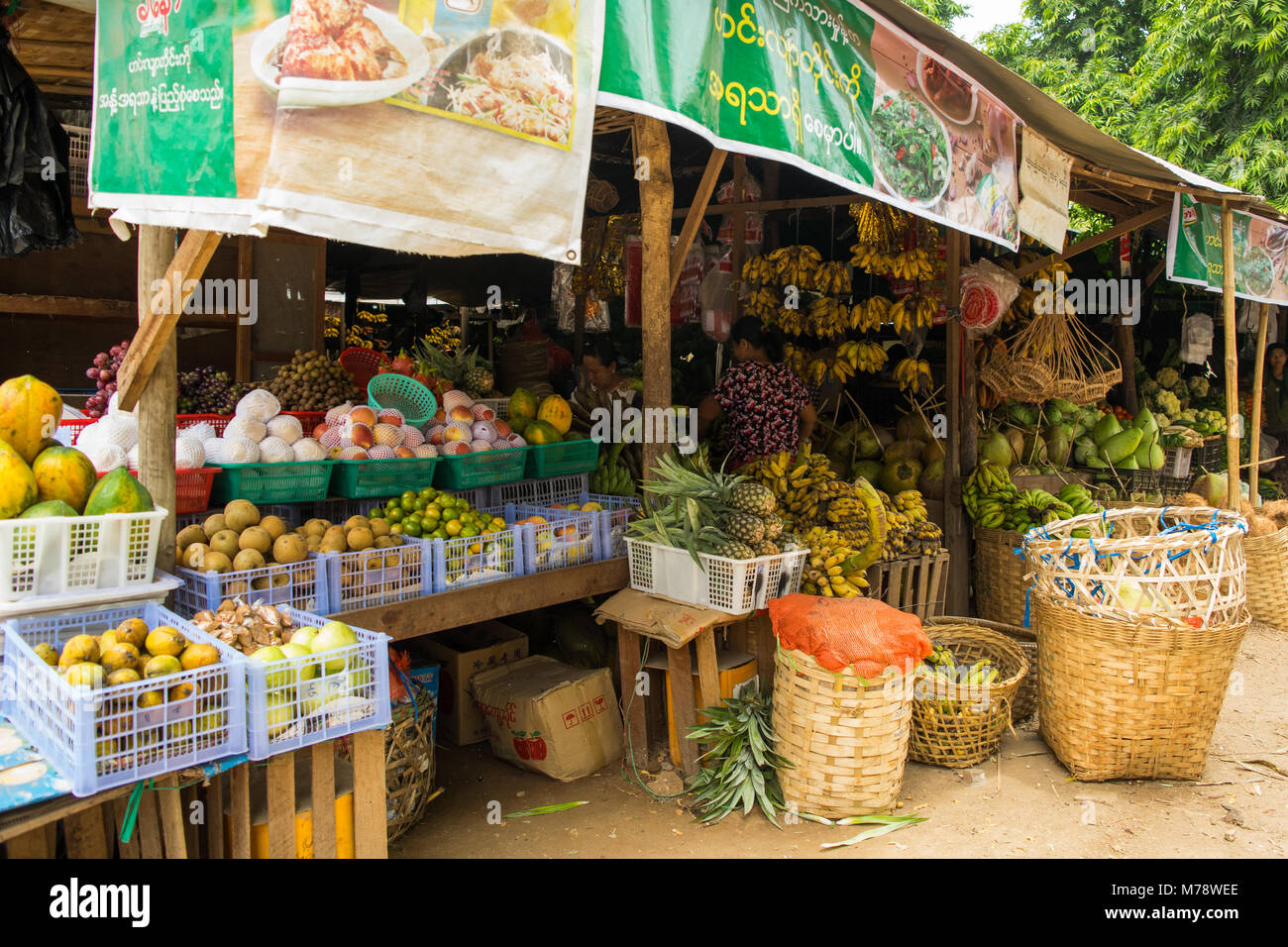 Burmese Asian Nyuang U market stall woman selling different fruit and vegetables in crates and cane baskets, near Bagan, Burma, Myanmar, SE Asia Stock Photo