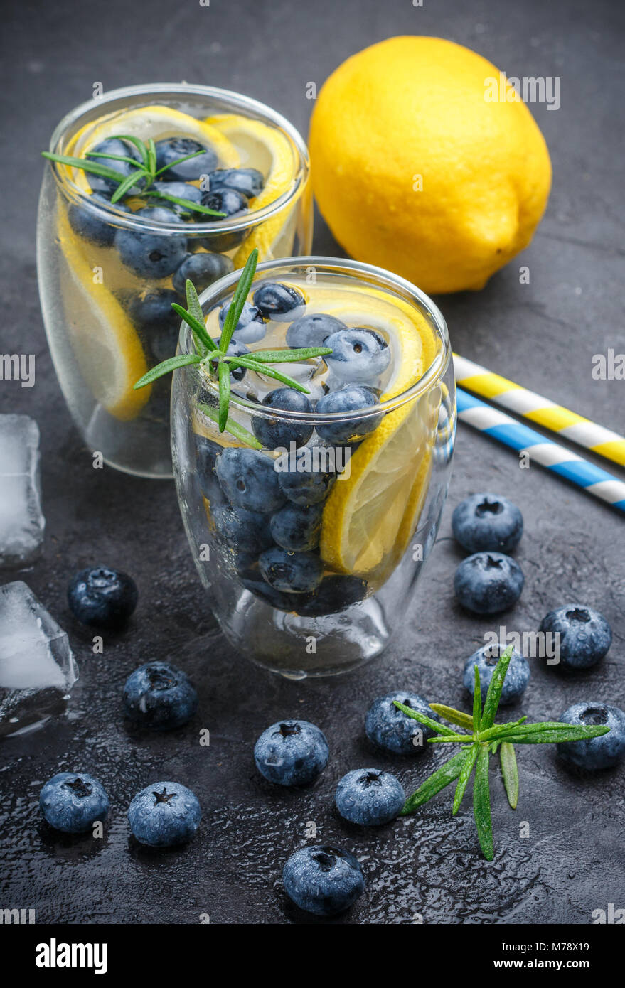 Refreshing summer drink with lemon, blueberries, rosemary and ice cubes ...