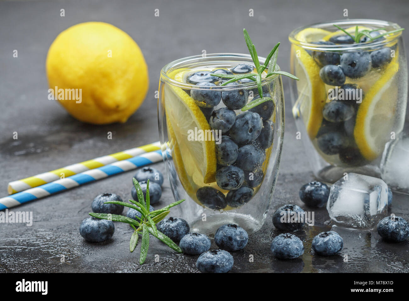 Refreshing summer drink with lemon, blueberries, rosemary and ice cubes ...