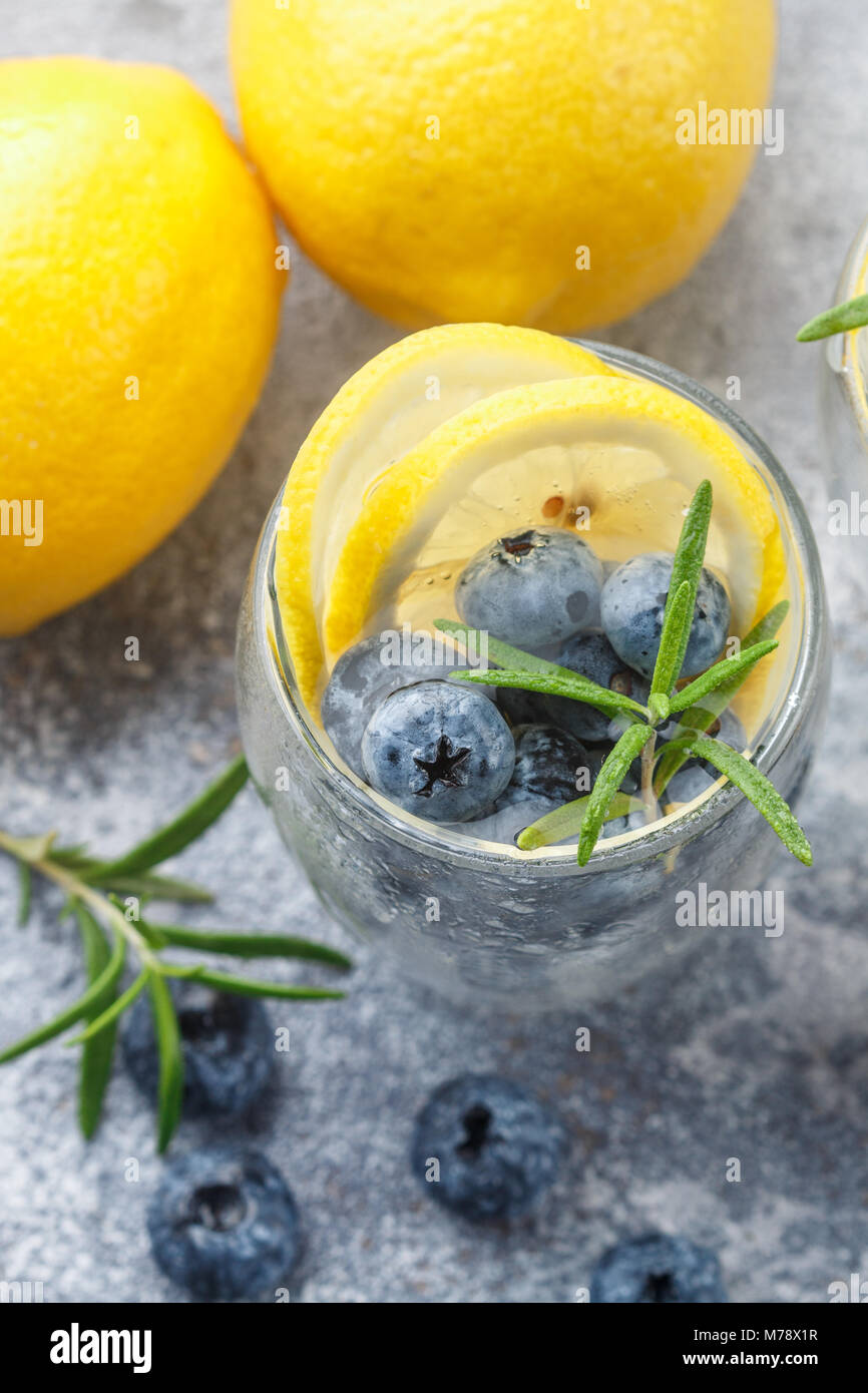 Refreshing summer drink with lemon, blueberries, rosemary and ice cubes ...