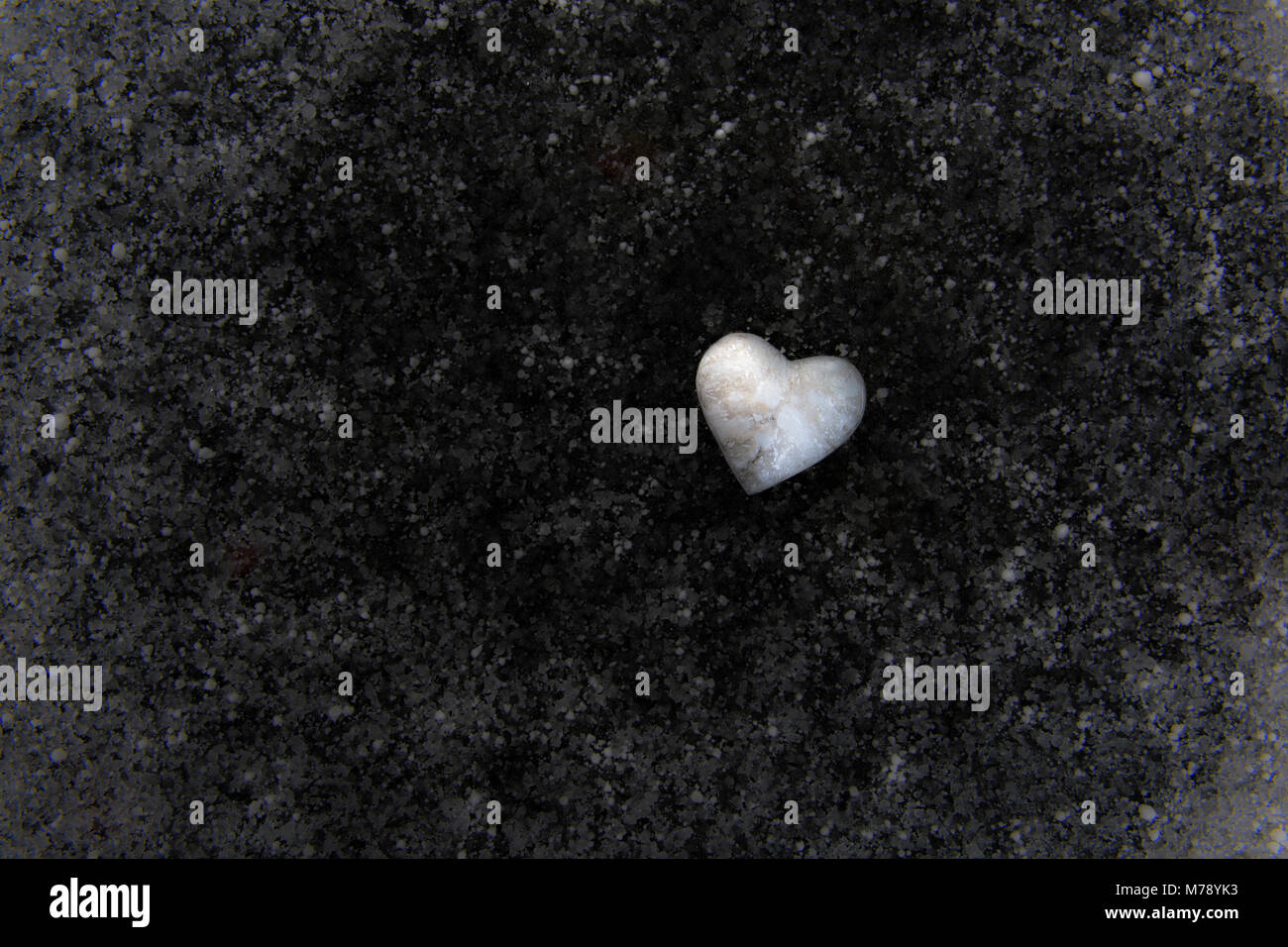 Small heart of marbled polymer clay on background of frozen snow and ice over pond. Stock Photo