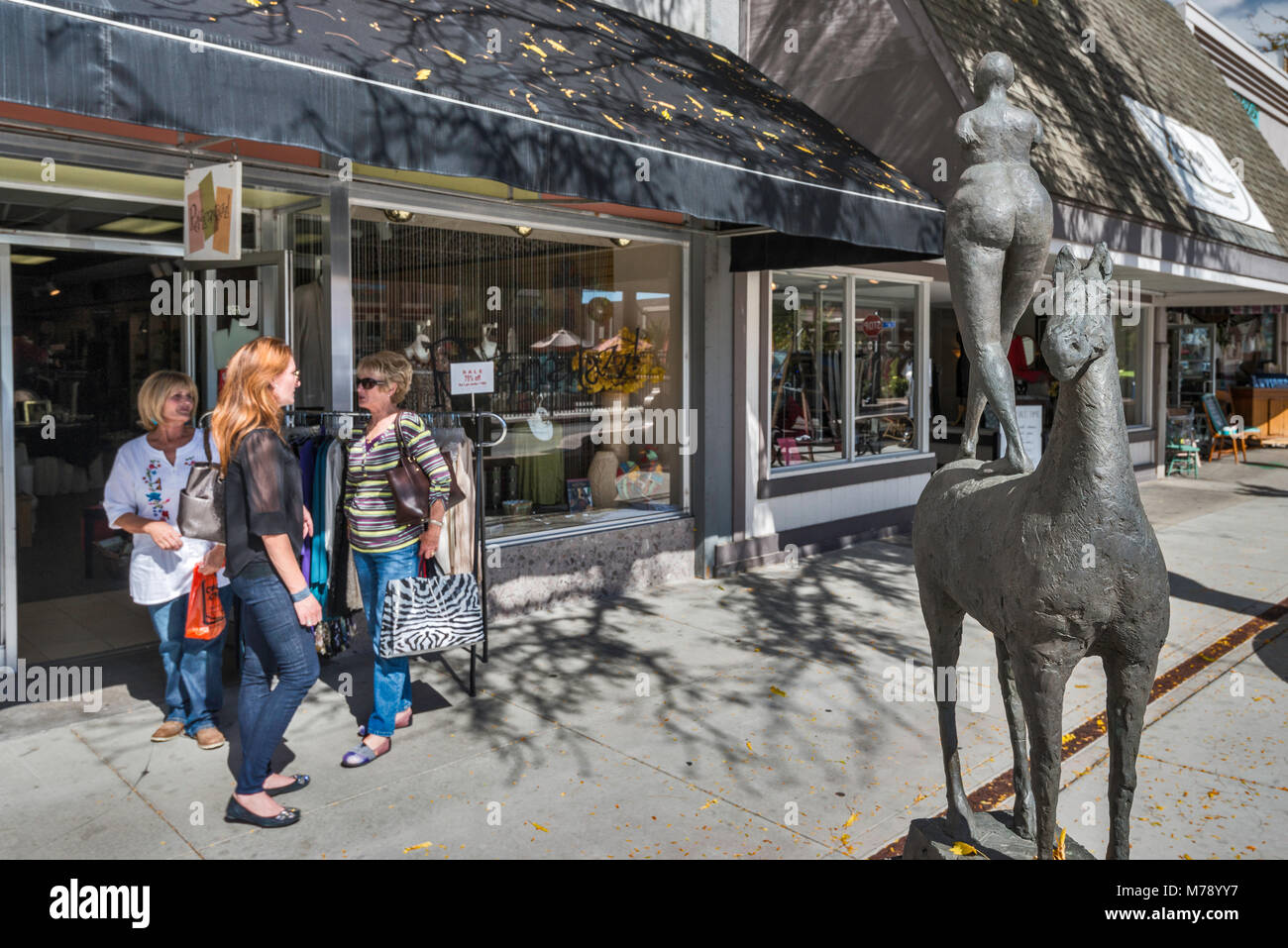 Women at store entrance, Horse and Rider sculpture by Philip Maior, Art on the Corner program, at Main Street Mall in Grand Junction, Colorado, USA Stock Photo