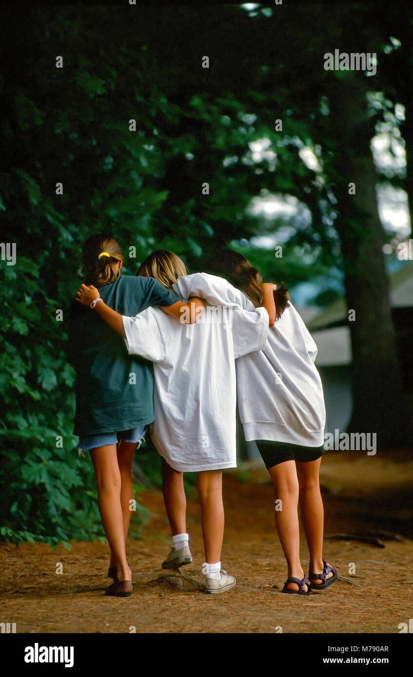 Three girls walk with their arms across each other's shoulders at summer camp in Vermont, United States, North America. Stock Photo