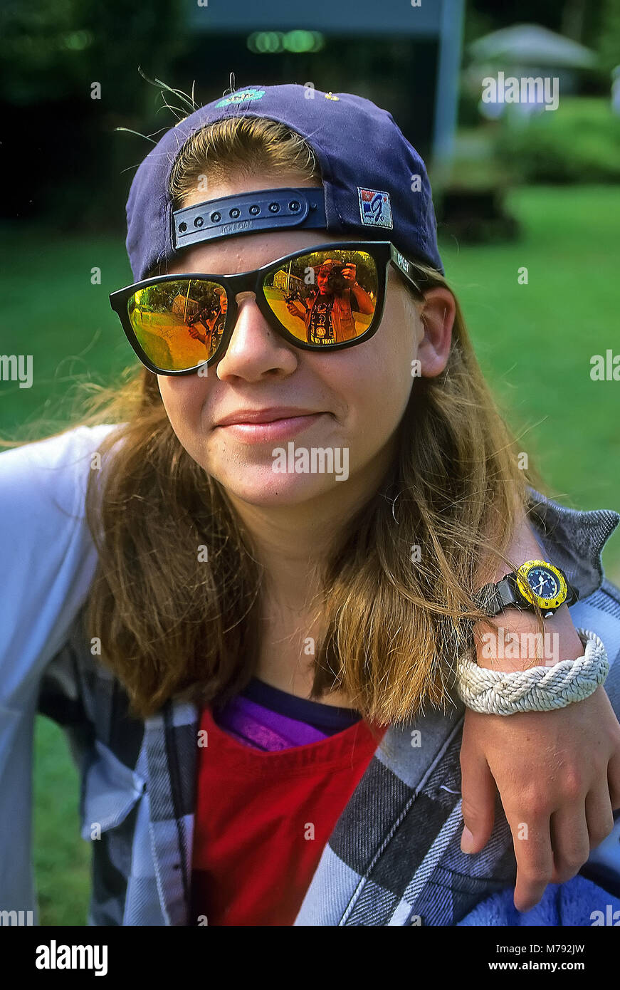 Portrait of a teenage girl about 16-19 years old at summer camp wearing reflector sunglasses and her hat on backwards in Vermont, USA. Stock Photo