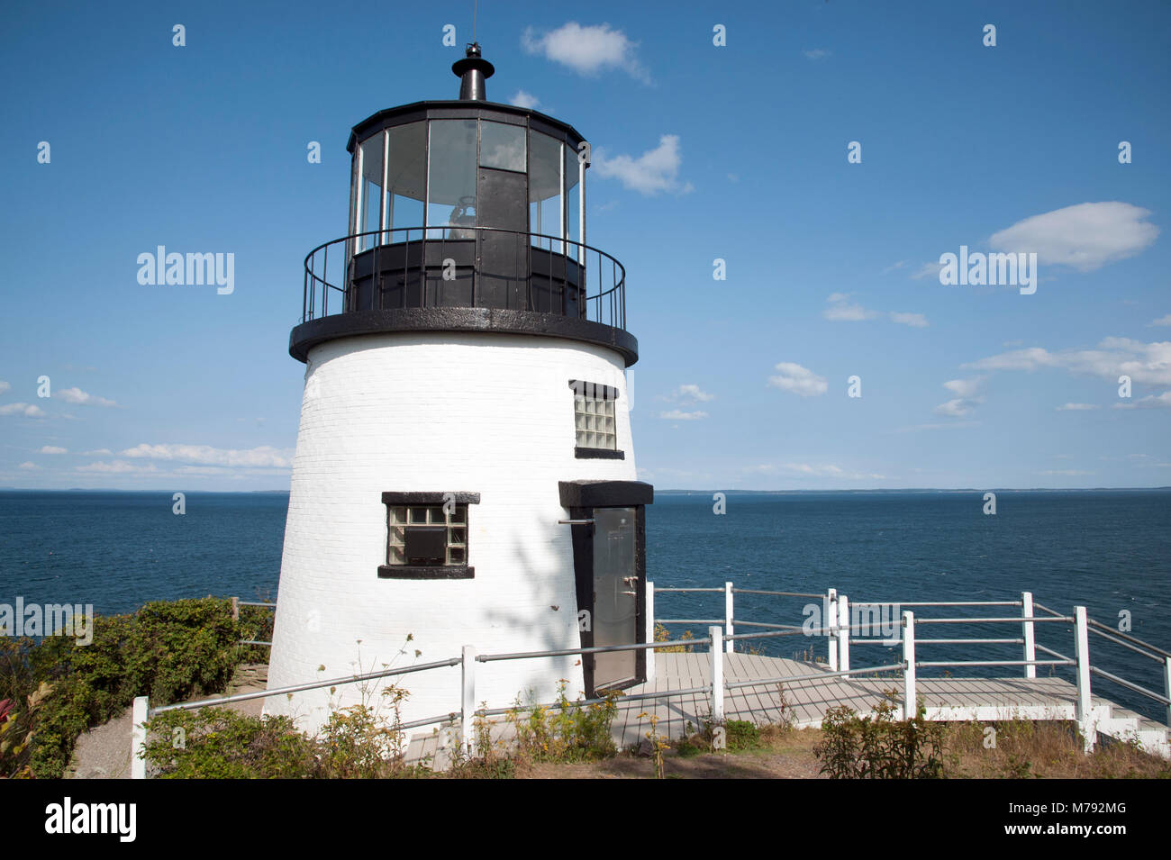 Owls Head lighthouse sits atop a 100 foot cliff over the ocean below, on a summer day in Maine. Stock Photo