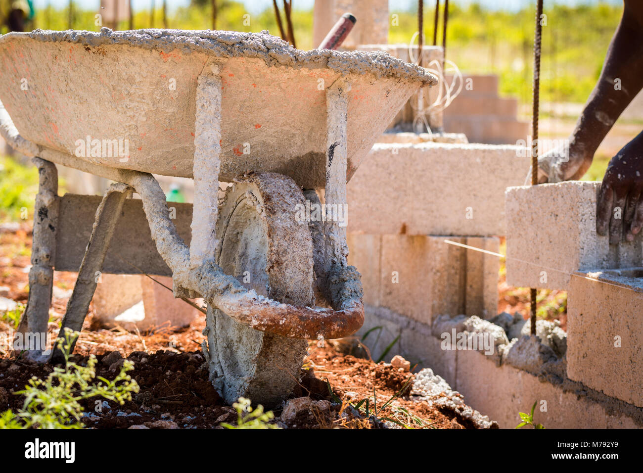 Hands of construction worker laying cement blocks over steel rods