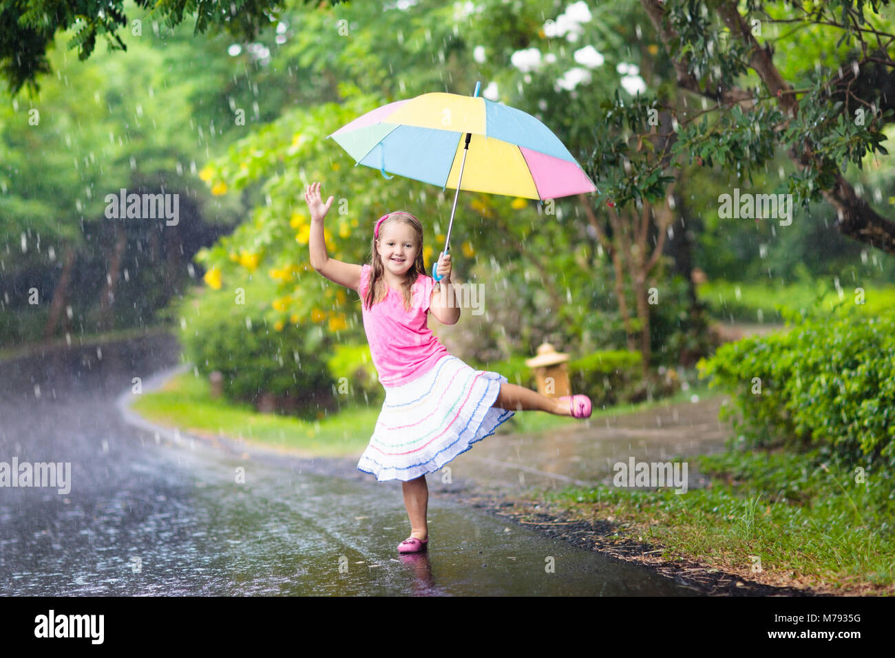 Kid playing out in the rain. Children with umbrella play ...