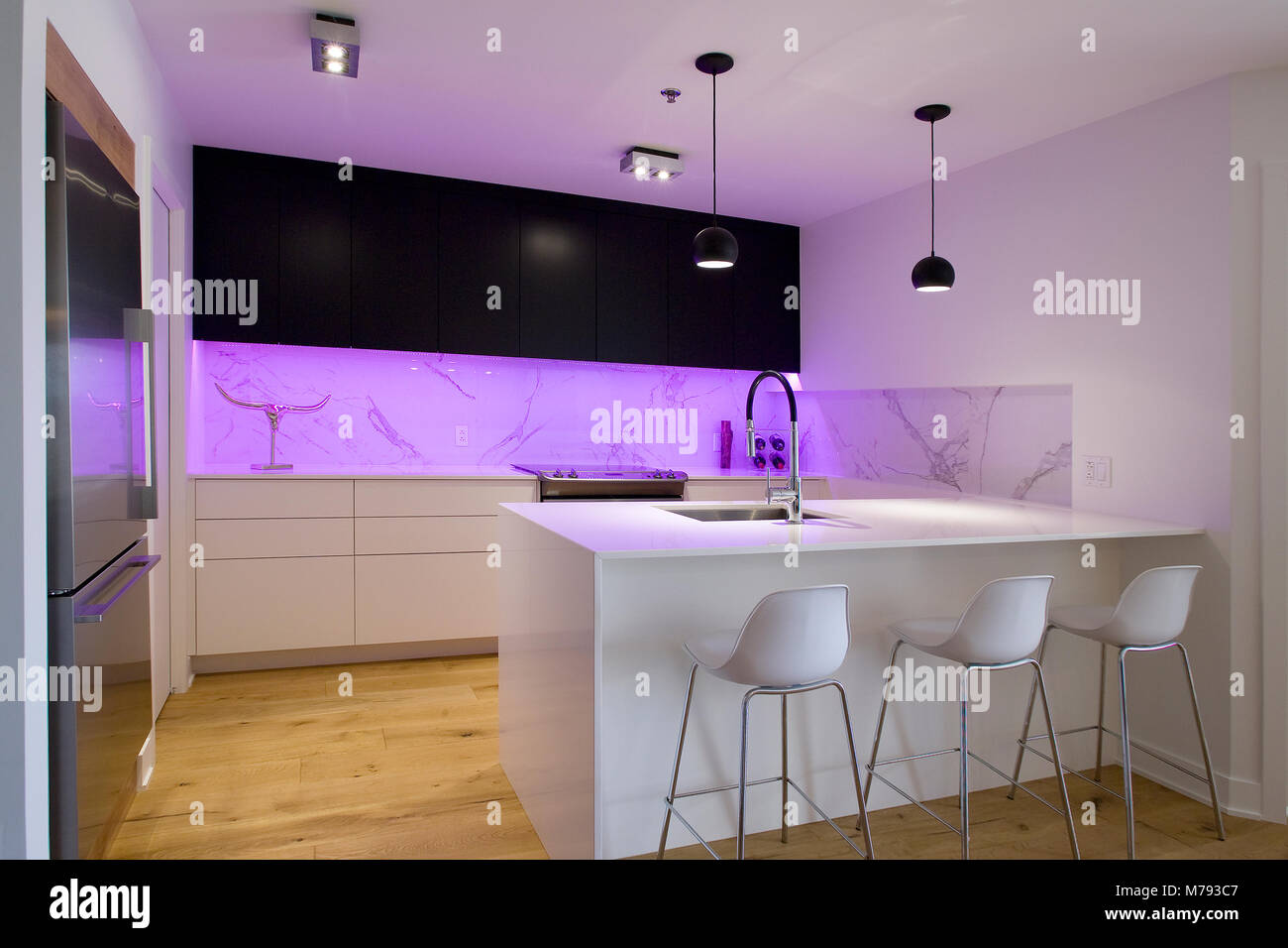 Black and white kitchen with island and stools and a purple lightning Stock Photo