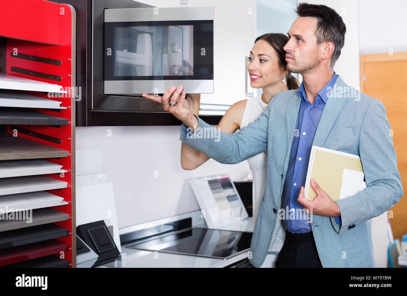 Young glad cheerful positive couple choosing microwave in household appliance section in furnishing store Stock Photo