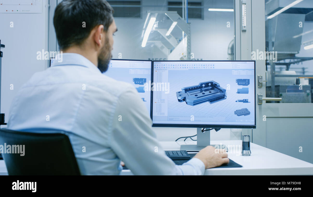 Engineer/ Technician Working on a Personal Computer with Two Displays, He's Designing New Component in CAD Program. Out of the Office Window Component Stock Photo