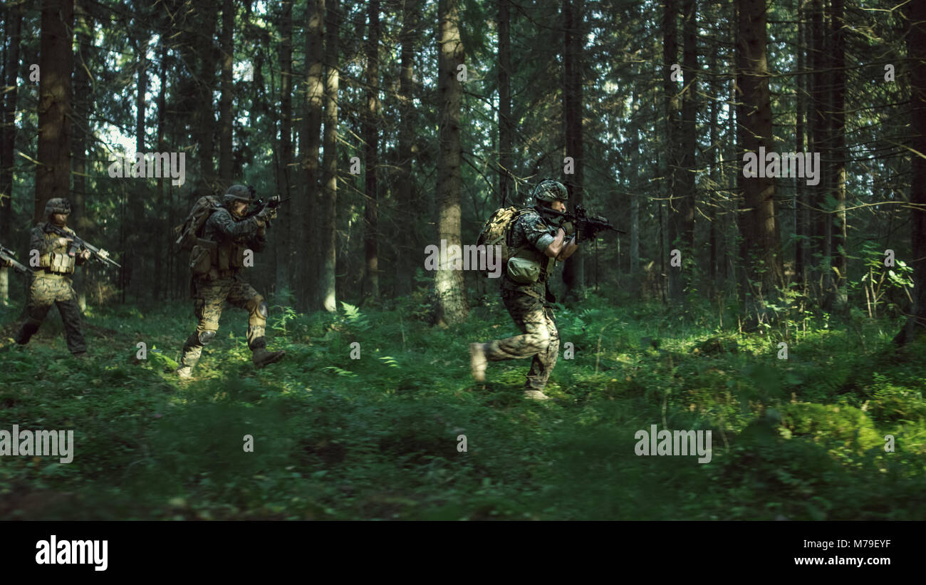 Fully Equipped Soldiers Wearing Camouflage Uniform Attacking Enemy, Rifles in Firing Position. Military Operation Action, Squad Running Through Forest Stock Photo