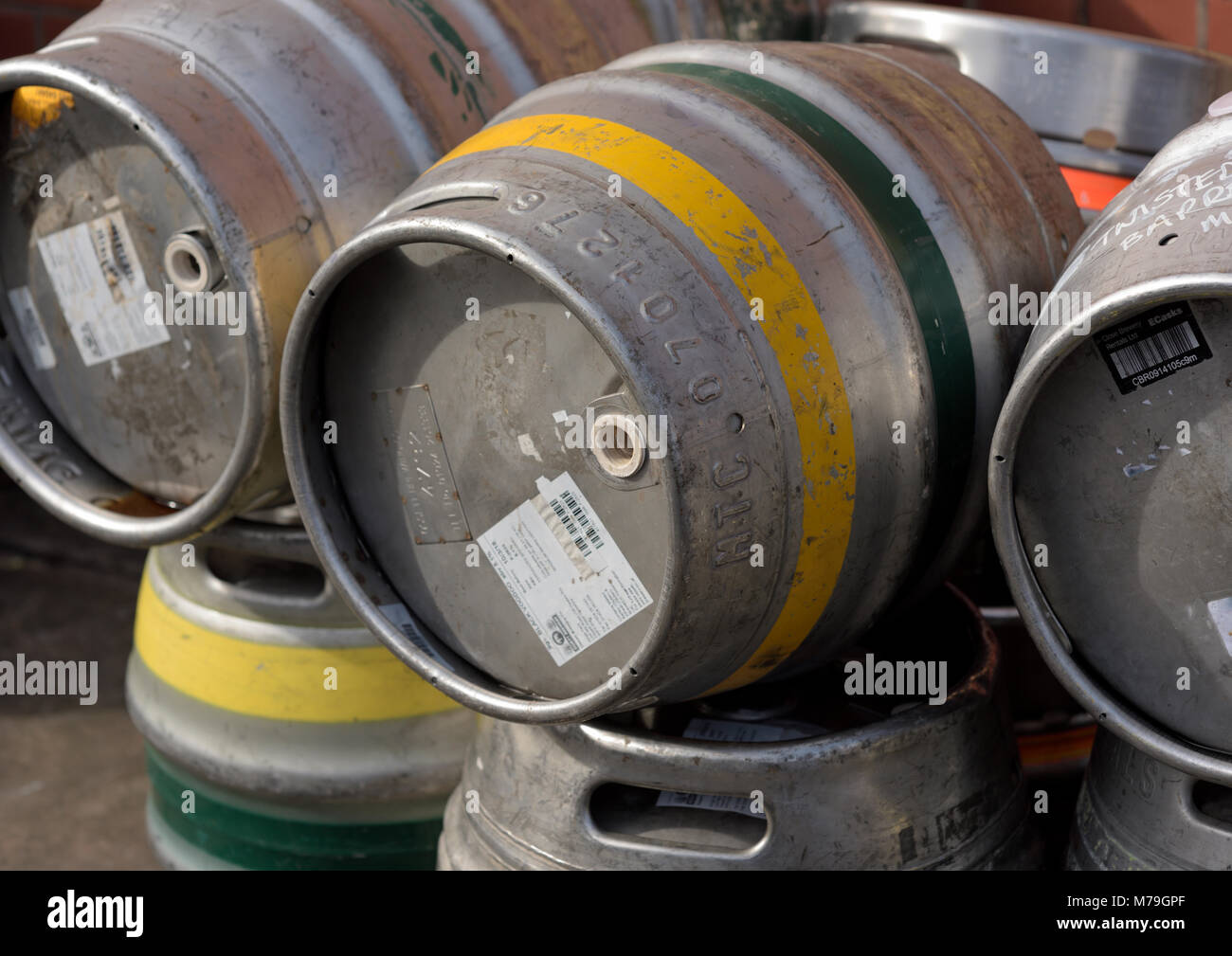 Stainless steel beer casks with yellow and green bands and labels in