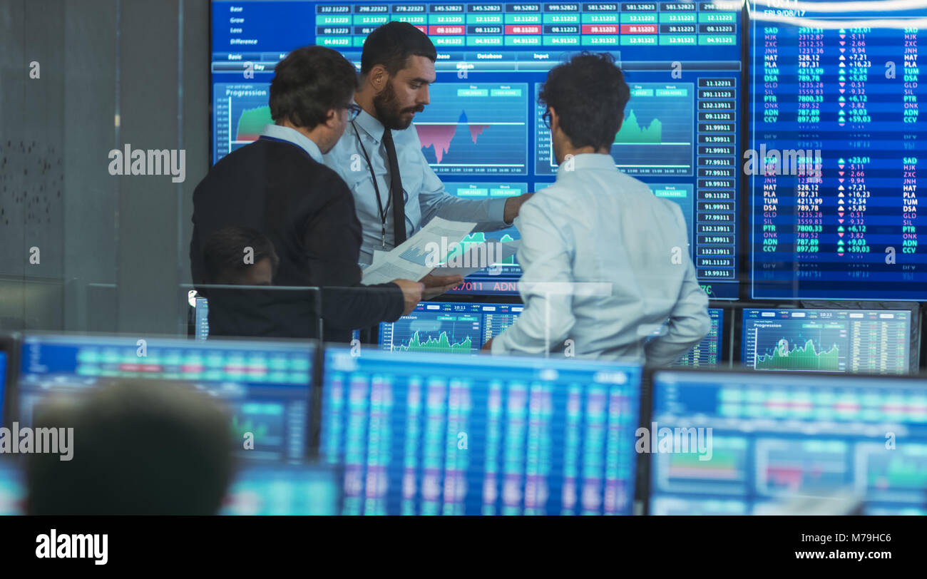 Three Experienced Stock Traders Talking Business, Consulting Documents and Argue About Data. They Work for a Big Stock Exchange Firm. Modern Office. Stock Photo