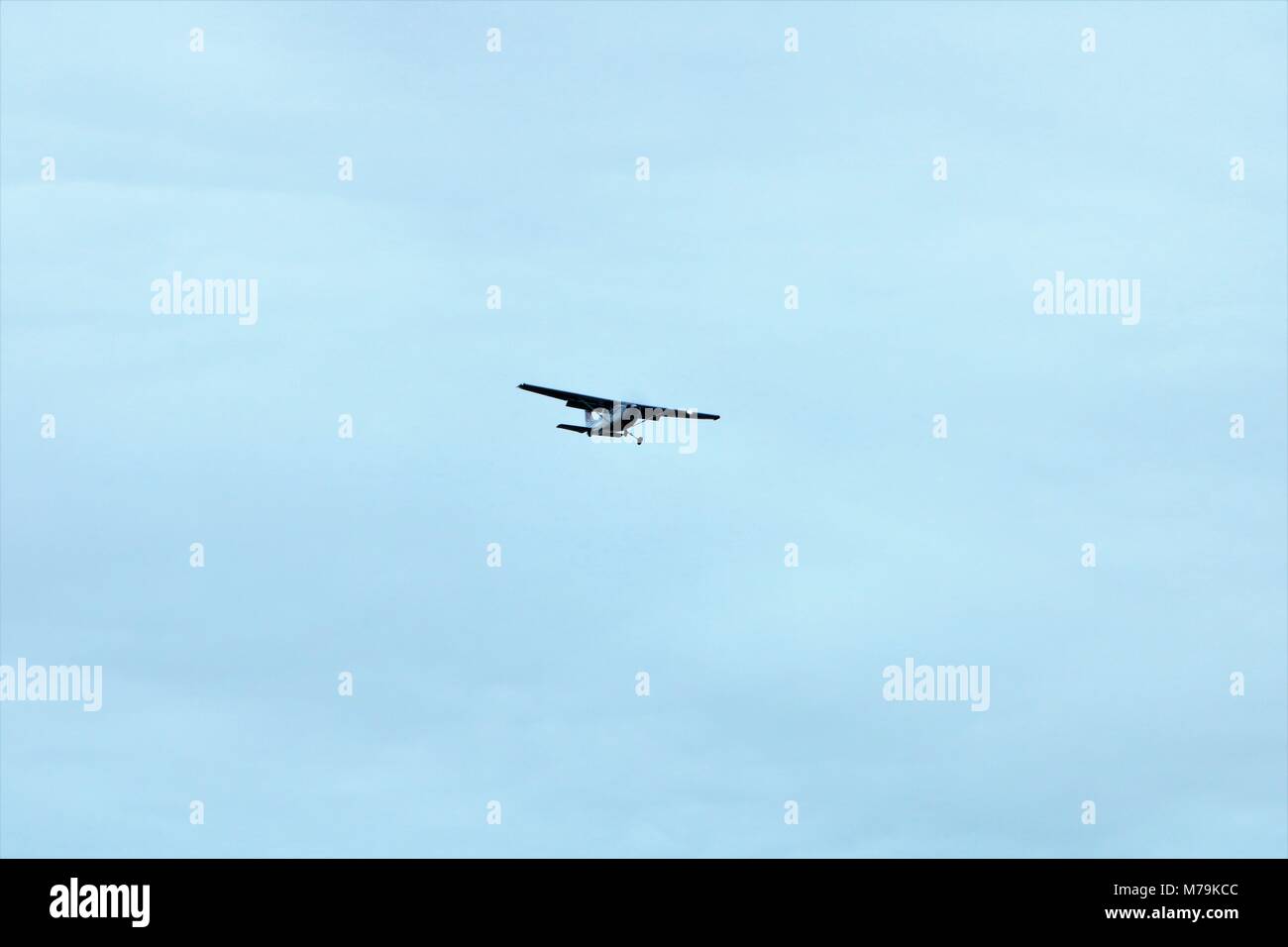 Cessna plane in mid flight in a blue cloudy sky Stock Photo