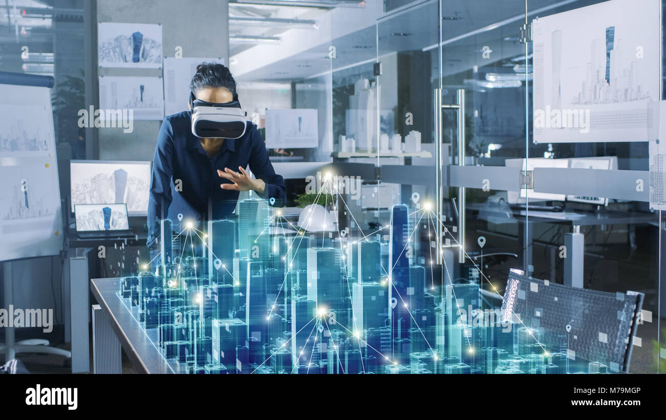 Professional Female Architect Wearing  Augmented Reality Headset Work with 3D City Model. High Tech Office Use Virtual Reality Modeling Software App Stock Photo