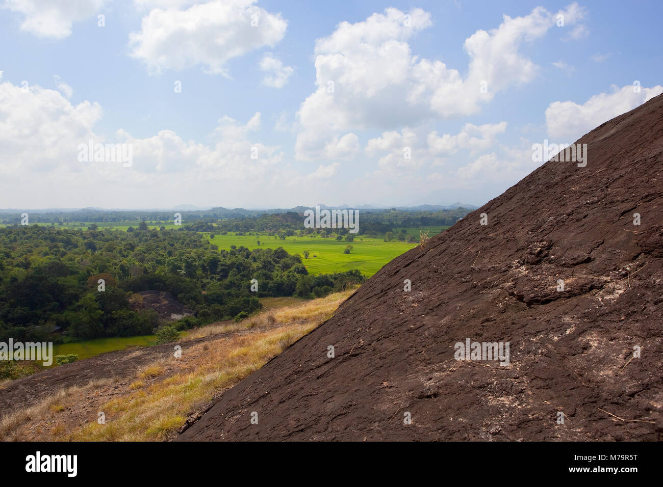 sri lankan volcanic rock formation in wasgamuwa national park with scenic landscape and hills under a blue sky with fluffy white clouds Stock Photo