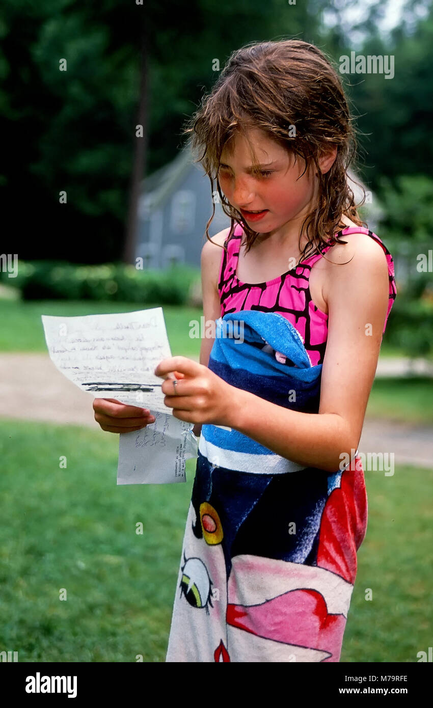 A young girl attending summer camp reads a letter from home in Vermont, United States, North America. Stock Photo