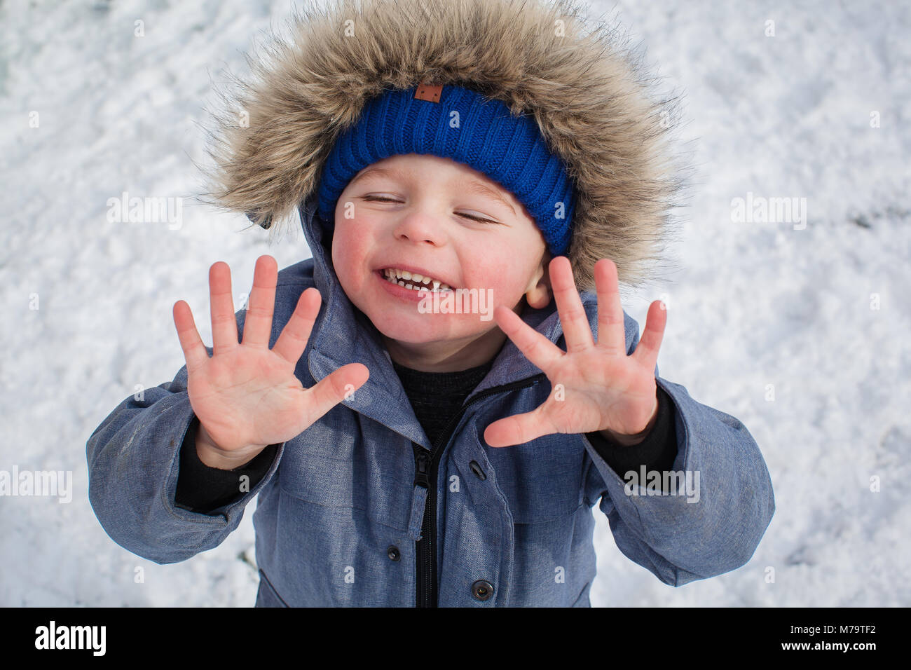 Young boy playing in the snow in their back garden Stock Photo