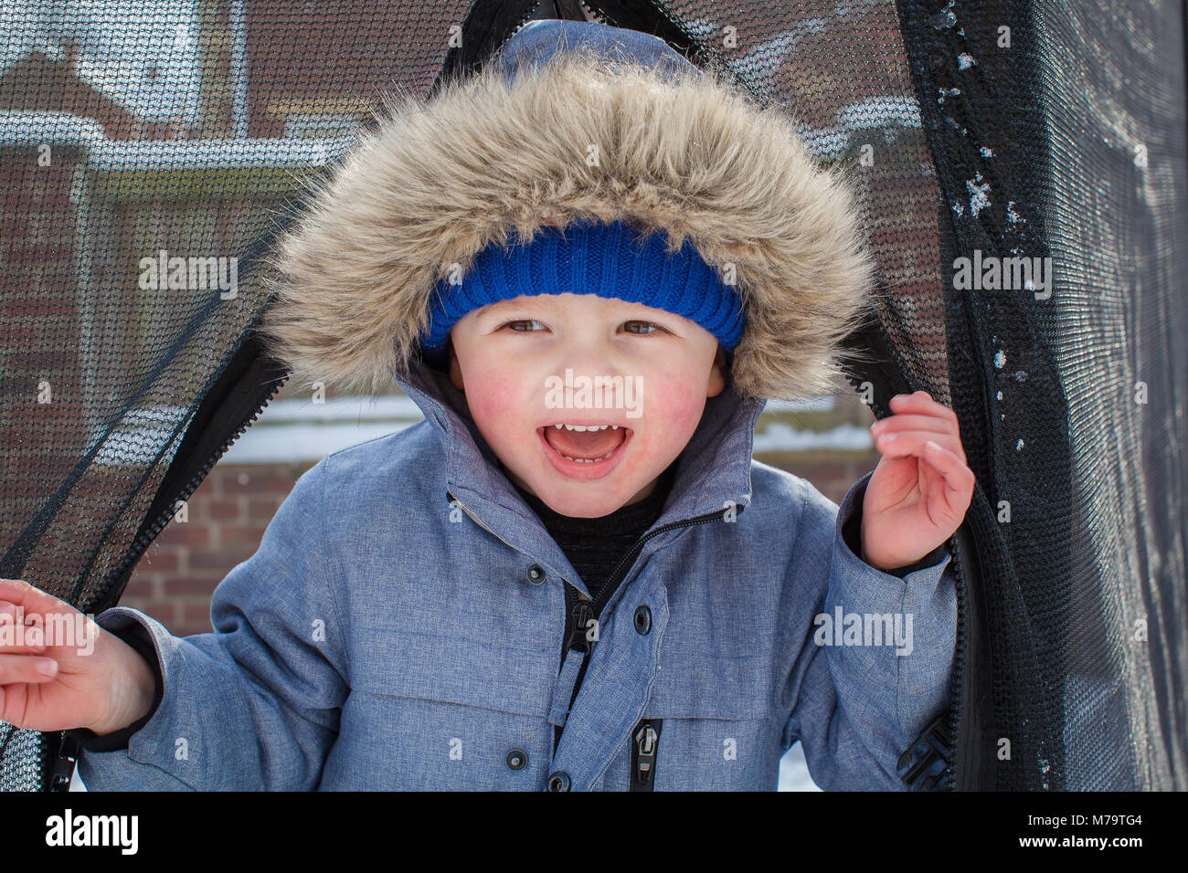 Young boy playing in the snow in their back garden Stock Photo