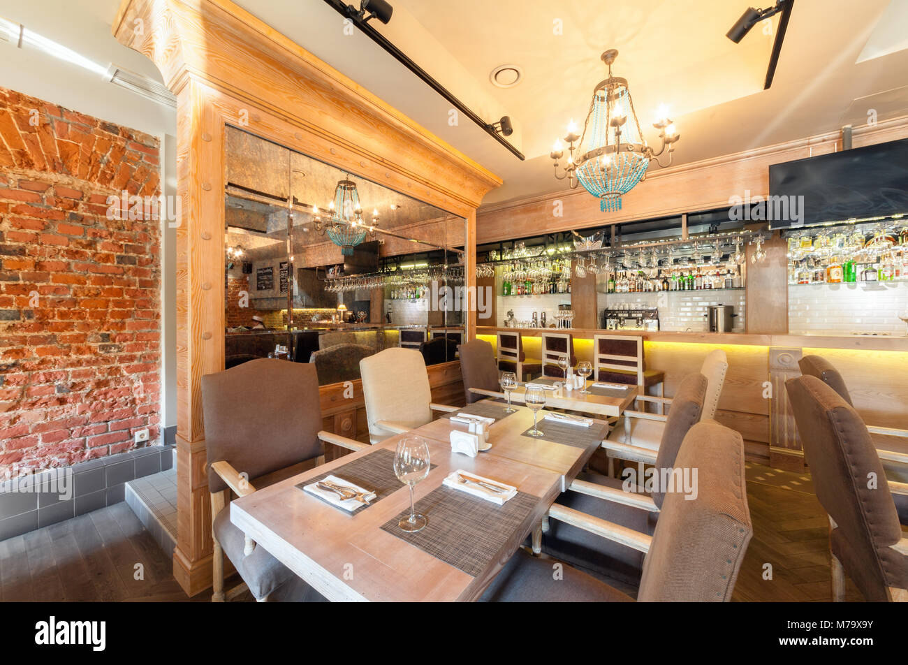 MOSCOW - AUGUST 2014: Interior elegant city restaurant 'RULET' in loft style. Table near the mirror in the main hall with a bar Stock Photo
