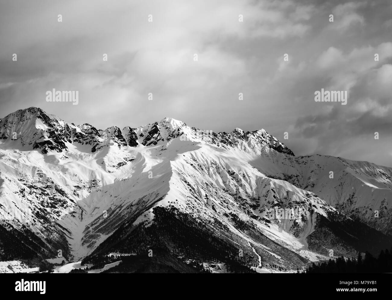 Snowy winter mountain and cloudy sky in evening. Caucasus Mountains. Svaneti region of Georgia. Black and white toned landscape. Stock Photo
