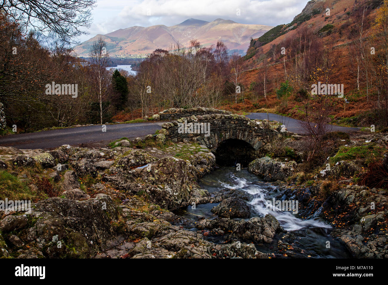 Historical Ashness Bridge, Lake District, England with stream, lake and mountains in autumn Stock Photo