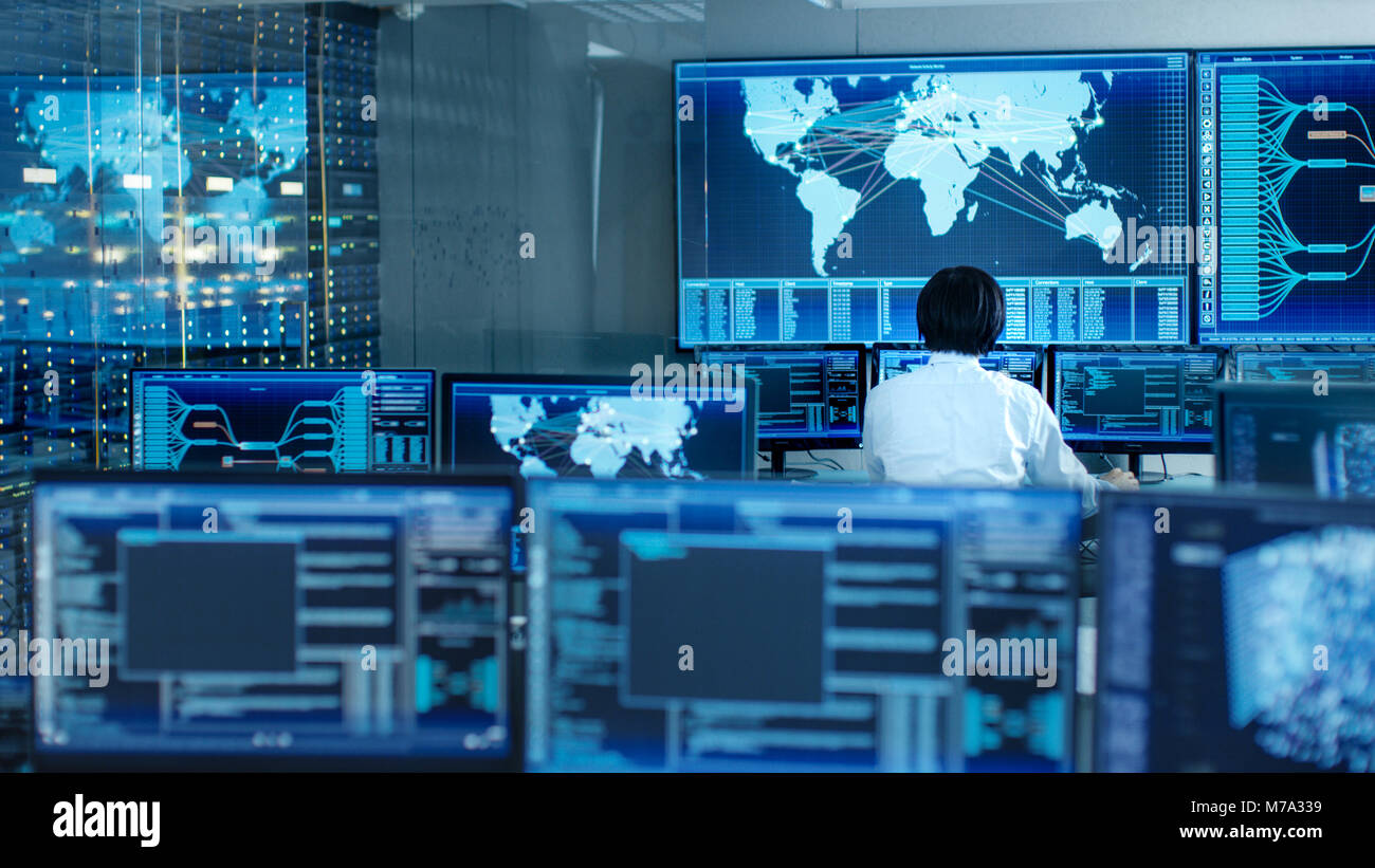 In the System Control Room Operator Sits at His Workstation with Multiple Displays Showing Graphics and Logistics Information. Stock Photo