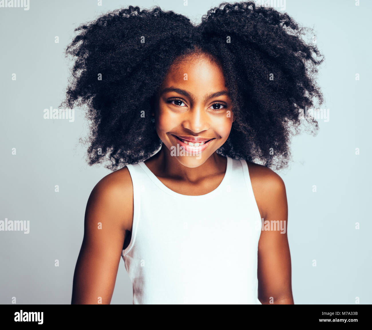 Happy young African girl with long curly hair smiling confidently while ...